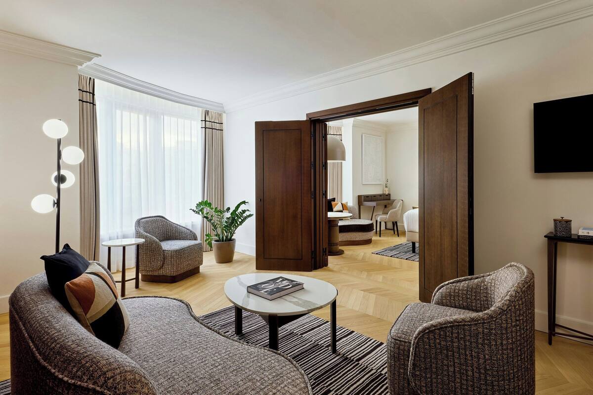 A modern living room with a sofa, armchairs, a coffee table, and a floor lamp.