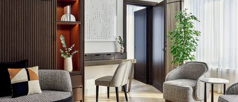 A modern living room with a sofa, armchairs, a coffee table, a bookshelf, and a large potted plant.