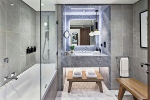 Een aparte badkuip en douche, designer toiletartikelen, een haardroger