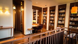 A library with wooden bookshelves, a chess table, and a comfortable reading chair. - Hotel Quartier Latin (Paris)