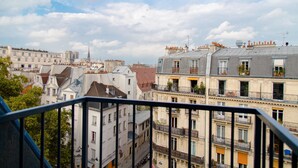A view of a cityscape with multi-story buildings, balconies with plants, and a clear sky. - Hotel Quartier Latin (Paris)