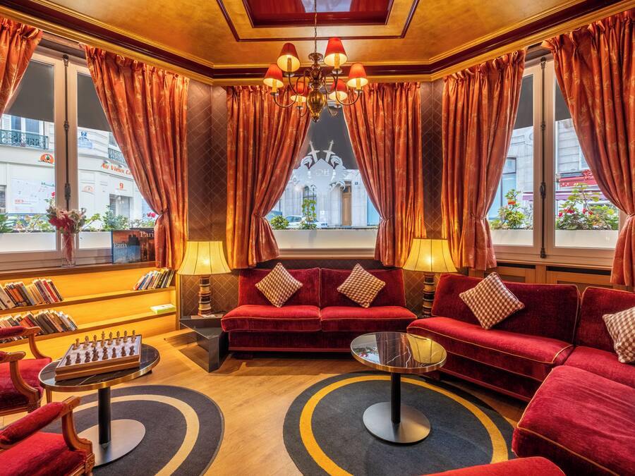 A luxurious room with a red sofa set, a chess table, and a chandelier.