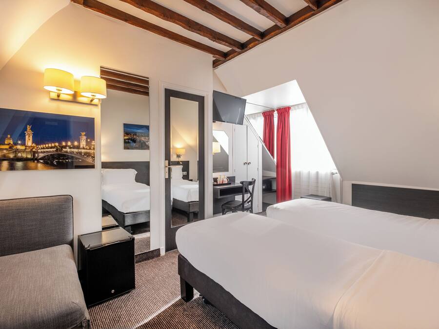 Une chambre d’hôtel avec deux lits, un bureau, une chaise, une télévision et un tableau représentant un paysage urbain.