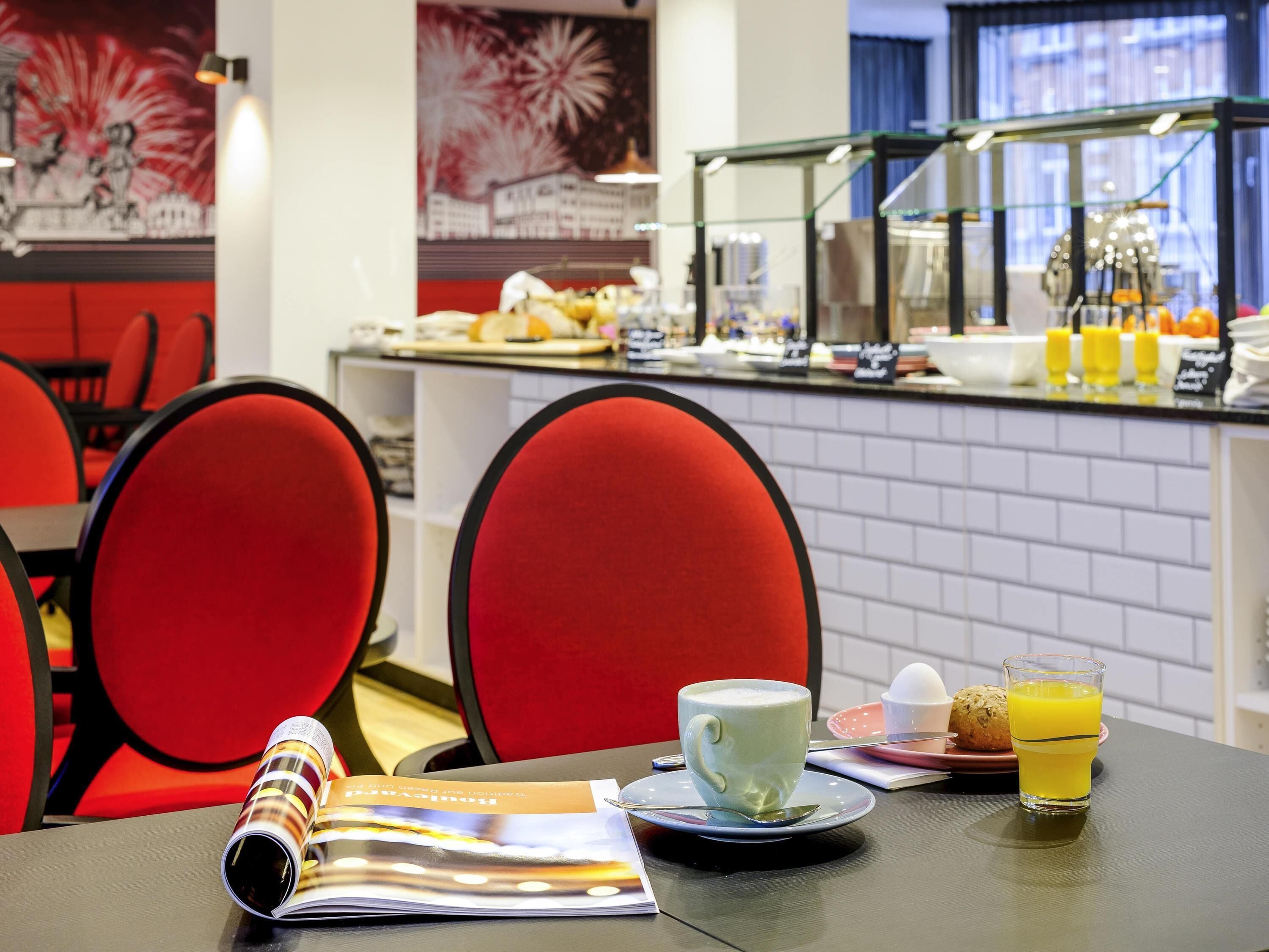 A breakfast setting with a magazine, a cup of coffee, a glass of orange juice, and a plate with a croissant.