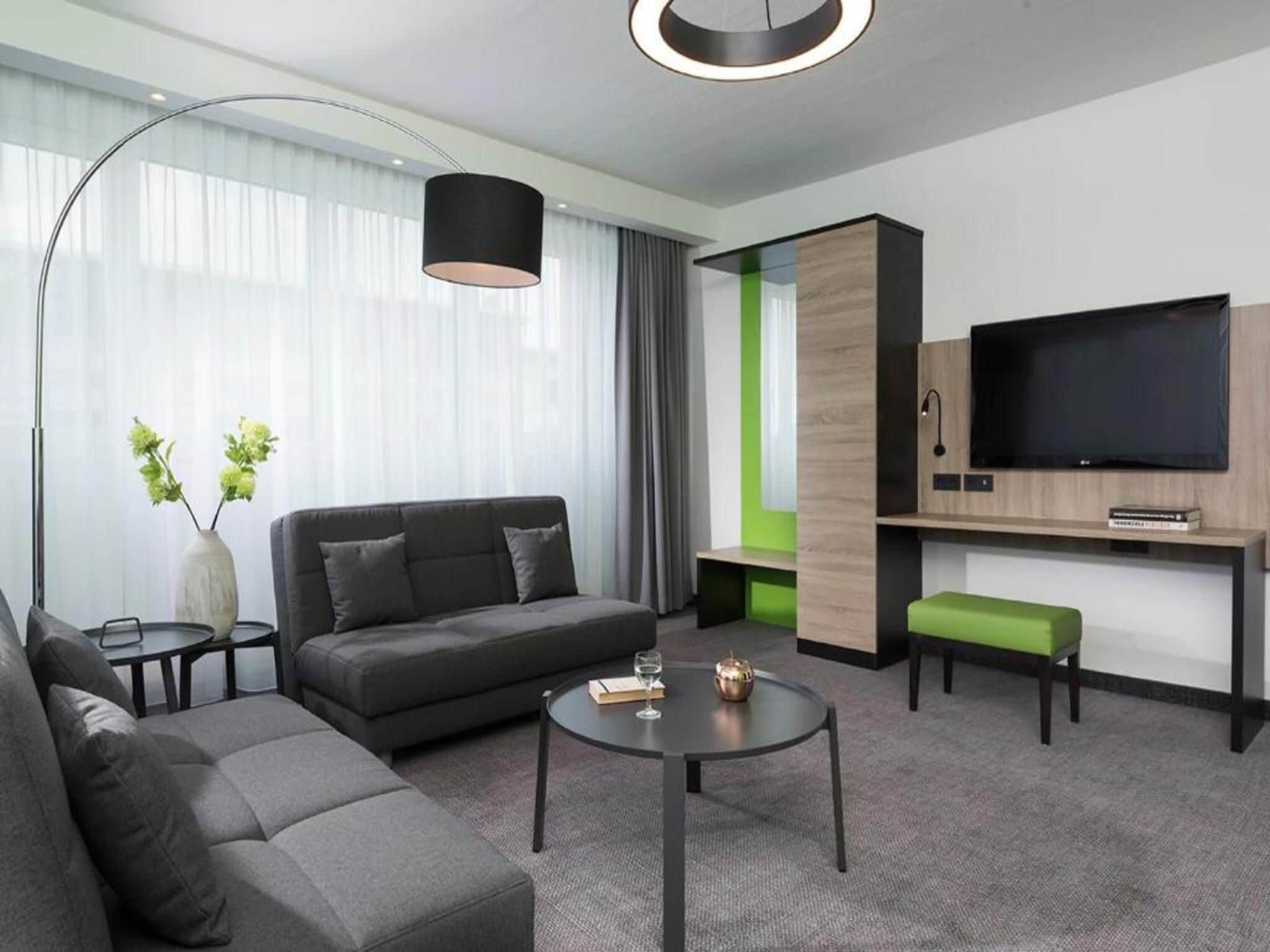 A modern living room with a sofa, coffee table, and a flat-screen TV mounted on a wooden panel.