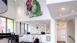 A modern hotel lobby with a high ceiling, a large mural, and a reception desk. - ibis Styles Halle (Halle (Saale))