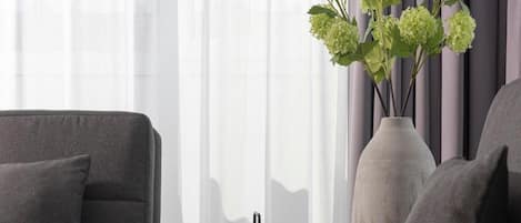 A modern living room with a grey sofa, a small round table, and a vase with green plants.