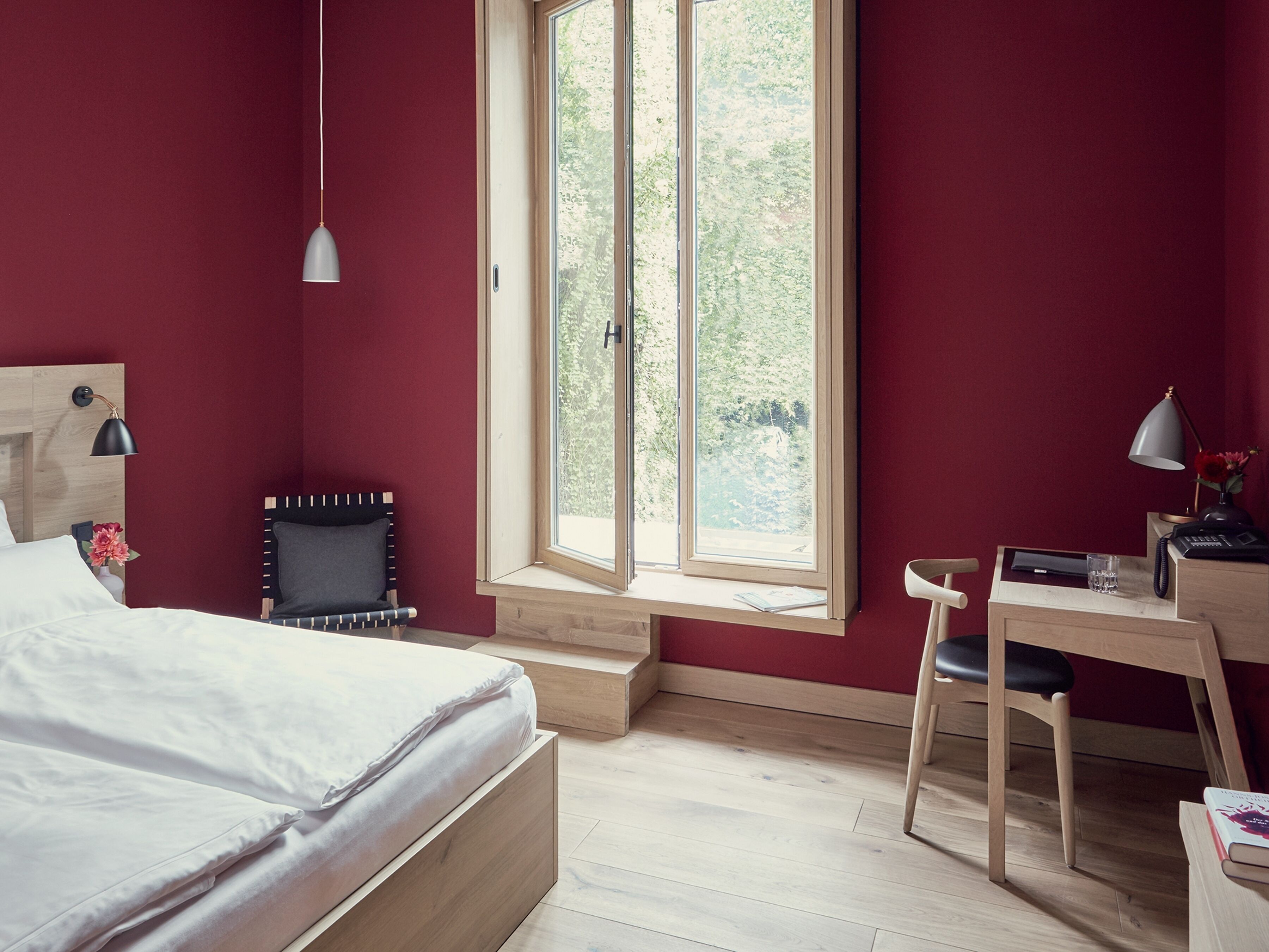 A bedroom with a bed, a desk, a chair, a window, and a lamp.