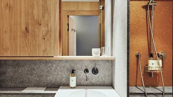 A modern bathroom with a wooden vanity, a sink, and a shower.
