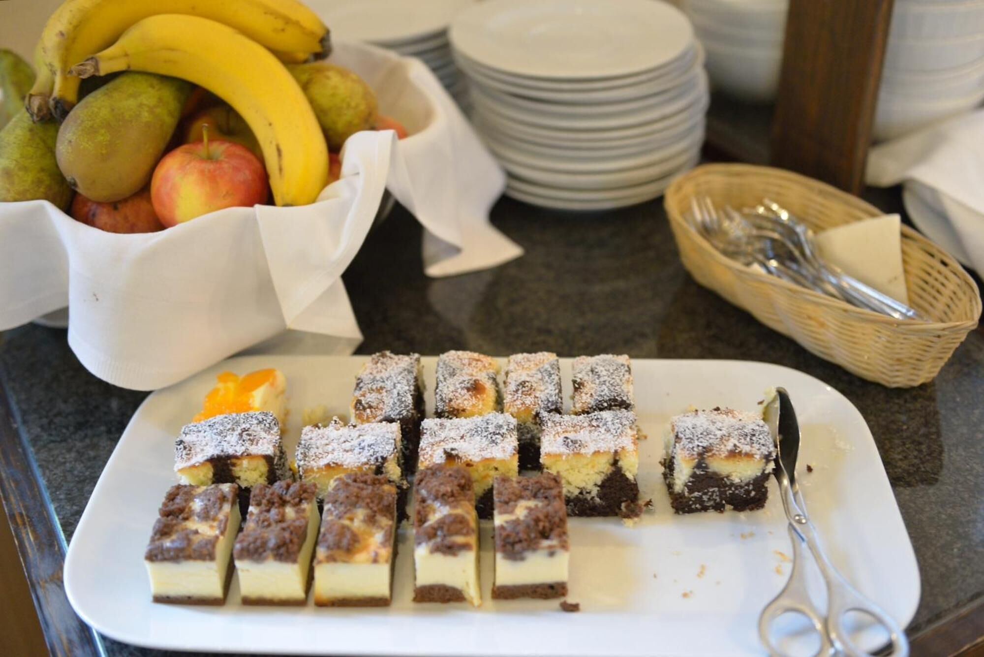 Une table de buffet proposant une variété de desserts, notamment une assiette de brownies et un saladier de fruits.