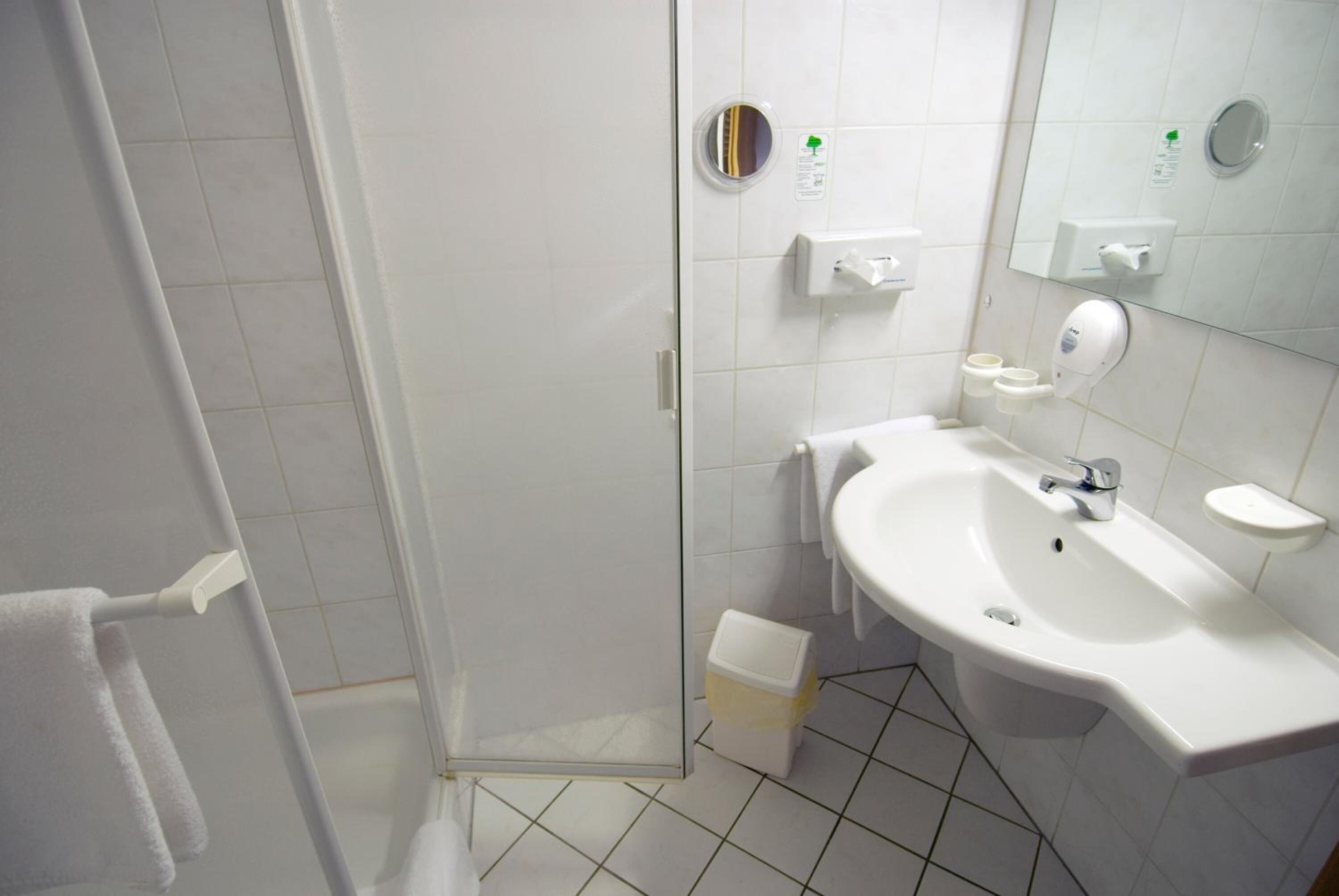 Une salle de bain moderne avec une douche à parois de verre, un lavabo blanc et un miroir.