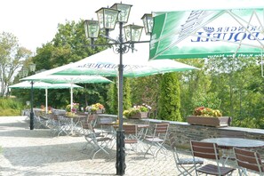 Outdoor seating with tables and chairs, surrounded by potted plants and a stone wall. - Land- und Golfhotel Alte Fliegerschule (Eisenach)