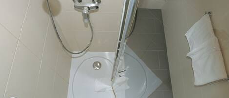 Un baño con ducha, inodoro y perchero para toallas.