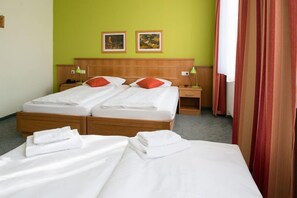 A double bed with white linens and red pillows, a wooden headboard, two bedside tables with lamps, and two framed pictures on the wall. - Land- und Golfhotel Alte Fliegerschule (Eisenach)