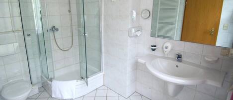 A modern bathroom with a glass-enclosed shower, a toilet, and a sink with a mirror above it.