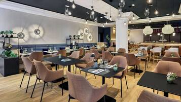 A modern restaurant interior with multiple dining tables and chairs, ambient lighting, and decorative wall elements.