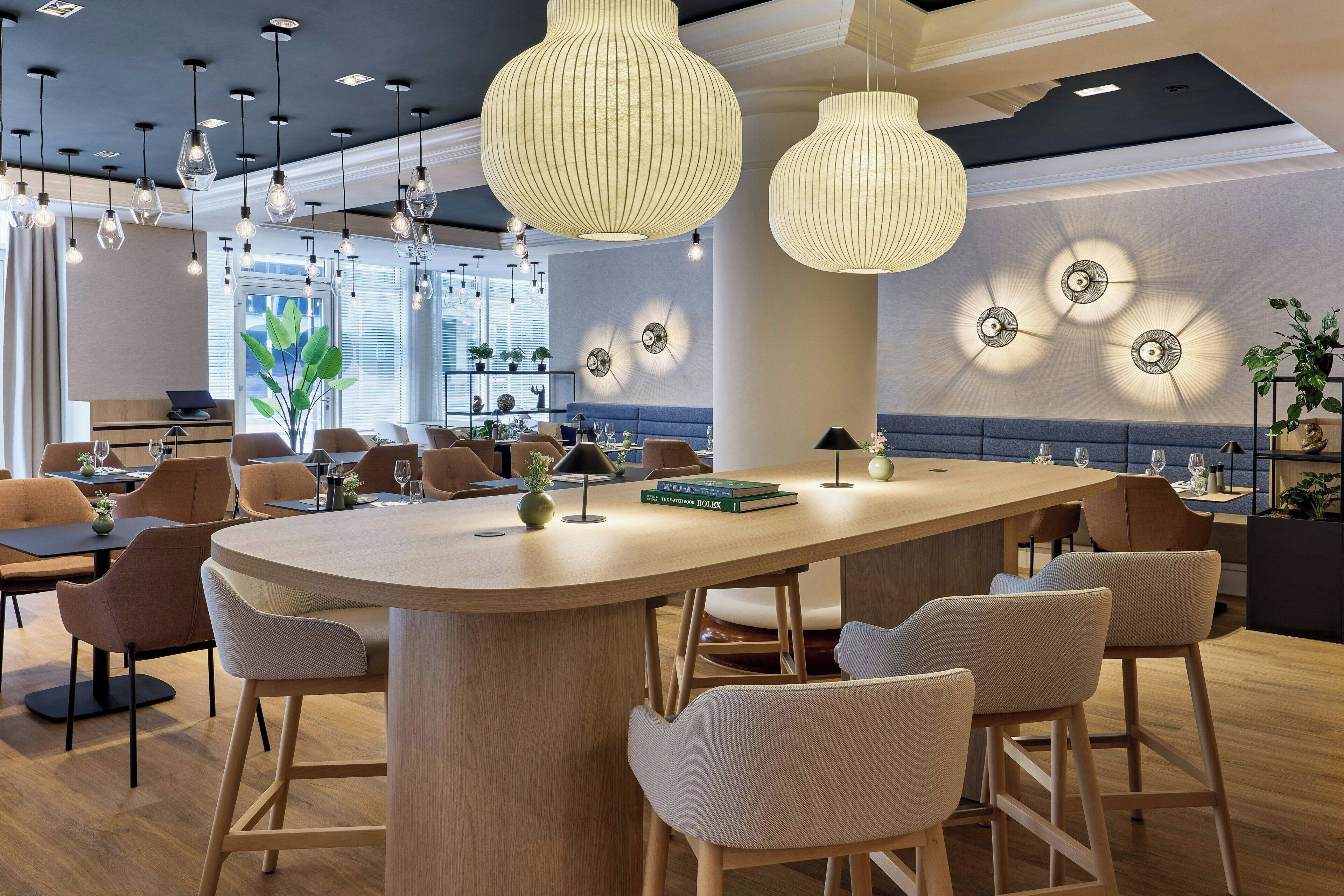 Un espace bar moderne doté d’un îlot central, de tabourets de bar et d’un éclairage suspendu.