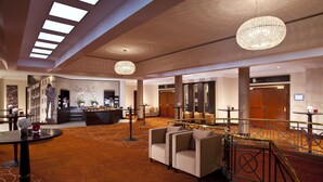 A spacious lobby with a high ceiling, a reception desk, a seating area with sofas, and a staircase with a railing. - Leipzig Marriott Hotel (Leipzig)