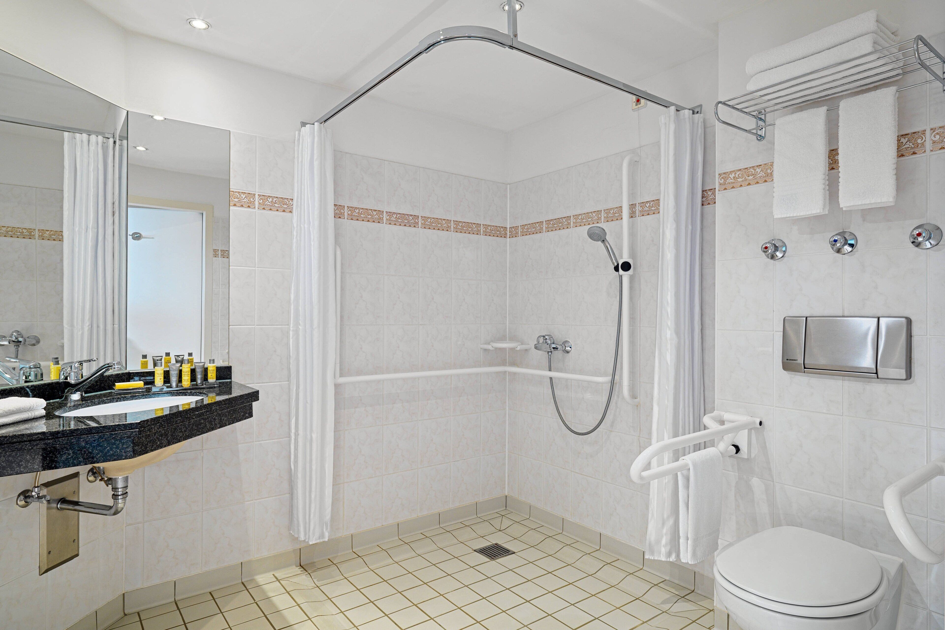 Een moderne badkamer met douche, toilet en wastafel.