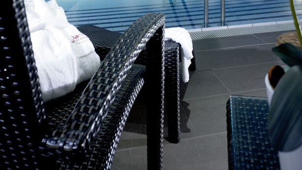 A spa area with a pool, reclining chairs, and a white orchid. - Leipzig Marriott Hotel (Leipzig)