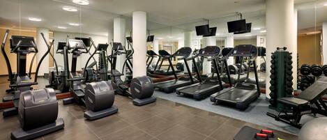 A gym with various cardio machines, weightlifting equipment, and exercise mats.