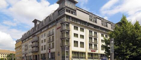 Un hôtel à plusieurs étages doté d’une architecture moderne, avec des balcons et de grandes fenêtres.