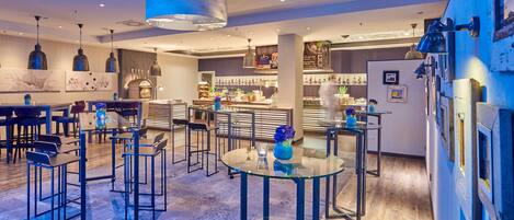 A modern interior with a bar area, seating arrangements, and a visible kitchen in the background.