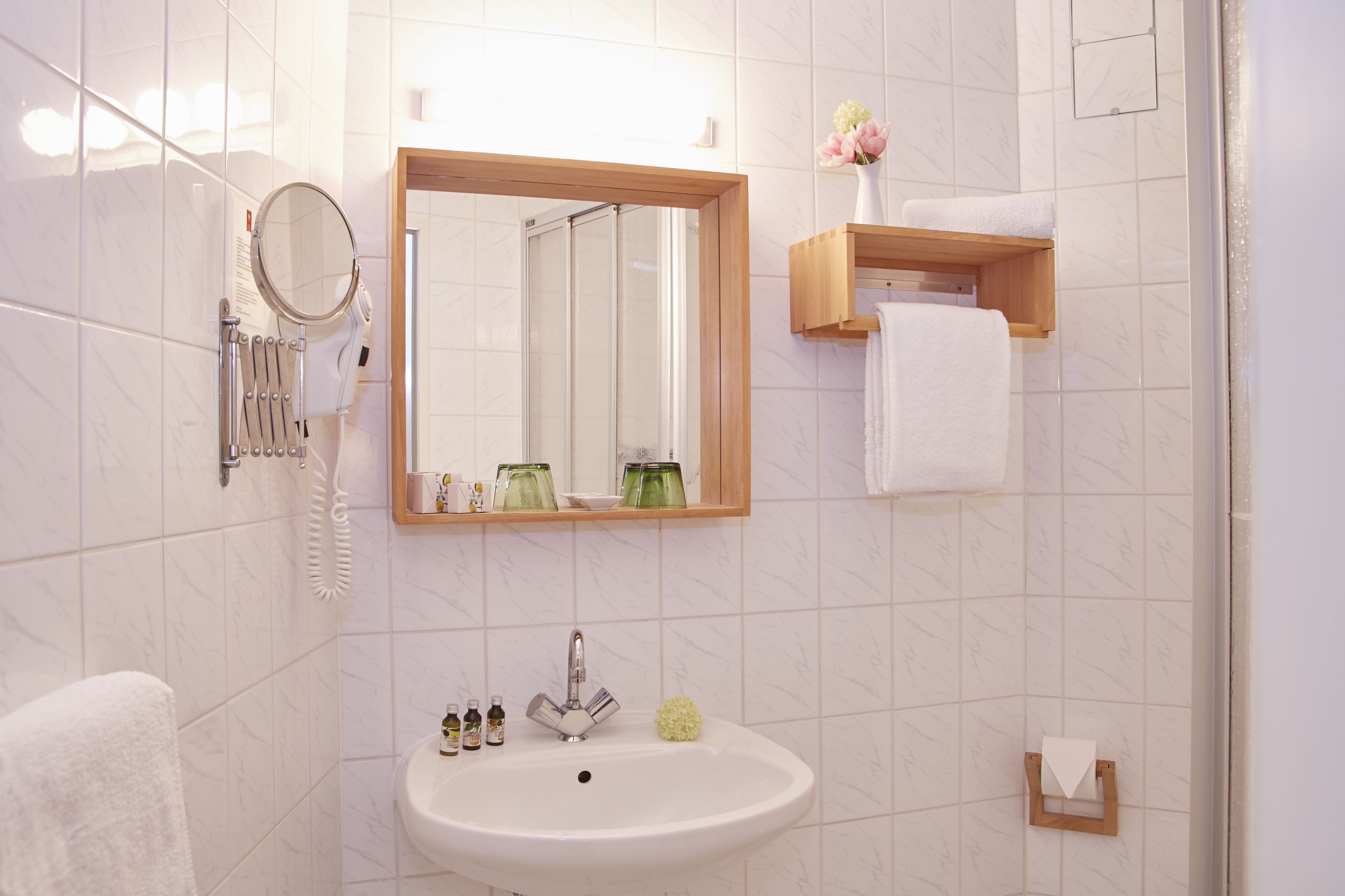 Un baño con lavamanos, espejo y toallero.
