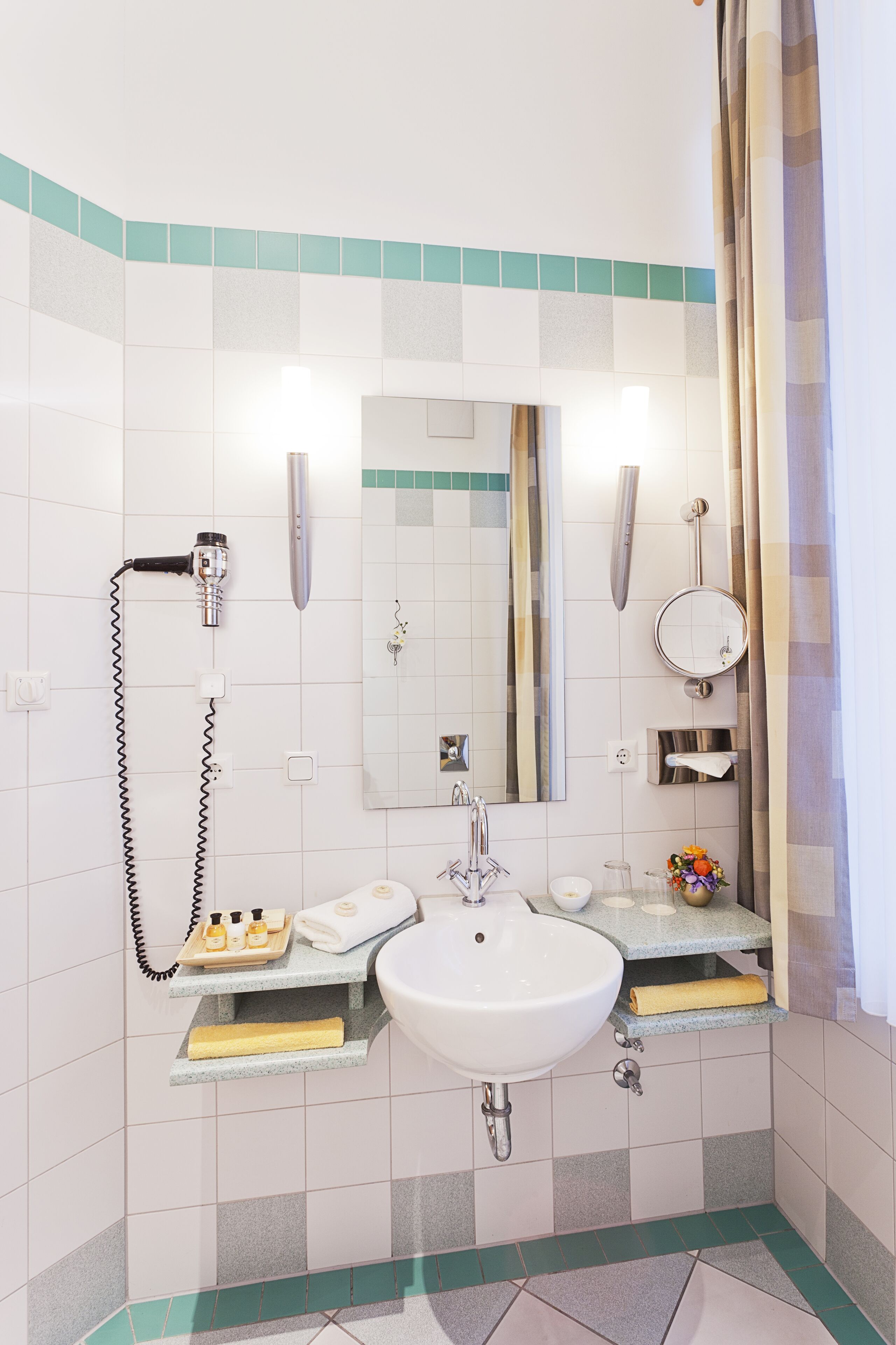 Une salle de bain équipée d’un lavabo, d’un miroir, d’un porte-serviettes et d’une pomme de douche.