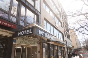 Un hotel con un letrero llamativo, una entrada visible y un edificio vecino con una cafetería.