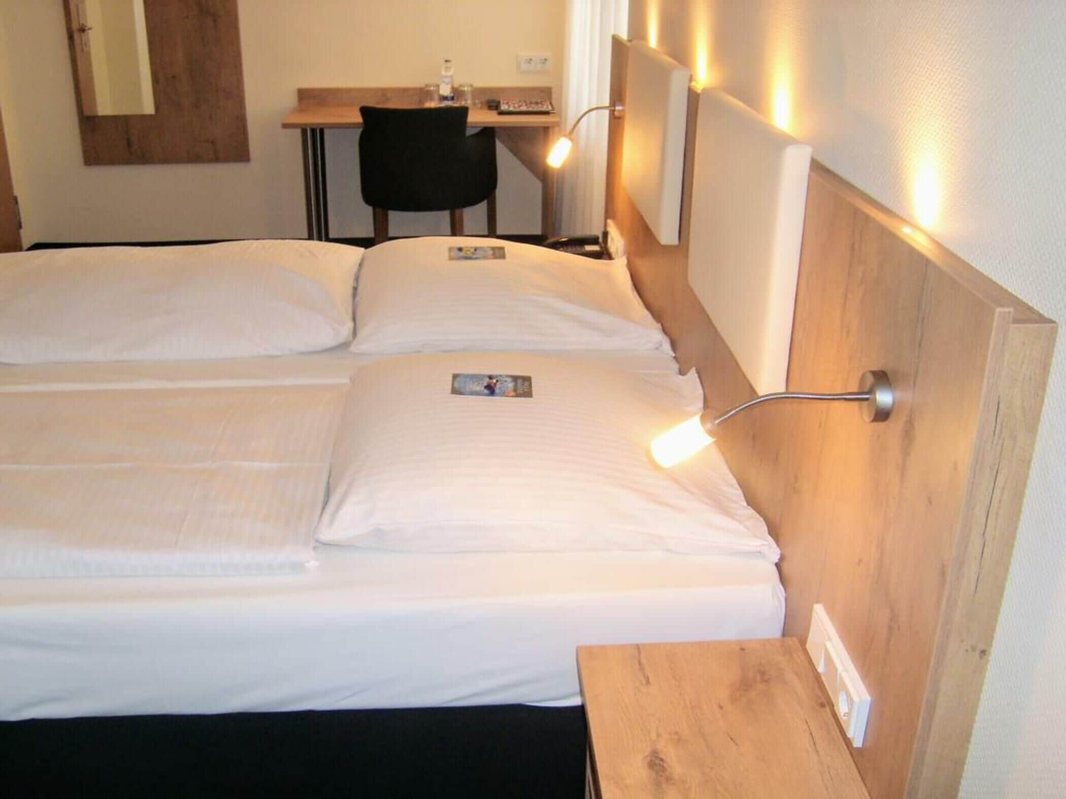 Ein Hotelzimmer mit zwei Betten, einem Schreibtisch und einem Stuhl.