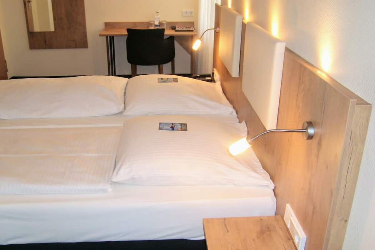 Ein Hotelzimmer mit zwei Betten, einem Schreibtisch und einem Stuhl.