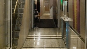 A hotel hallway with a glass door, a staircase, and a tiled floor.