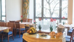 A dining area with tables, chairs, and a buffet with fruits and bread.