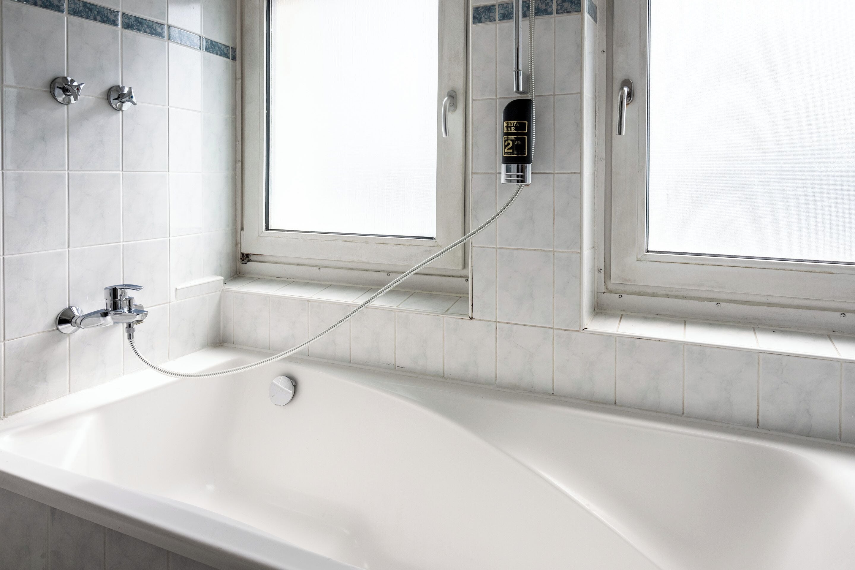 Un baño moderno con una bañera independiente, un cabezal de ducha manual y un panel digital de control de temperatura.
