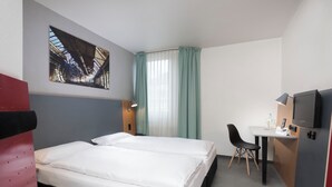 Une chambre d’hôtel avec deux lits, un bureau, une chaise, une télévision et un tableau au mur.