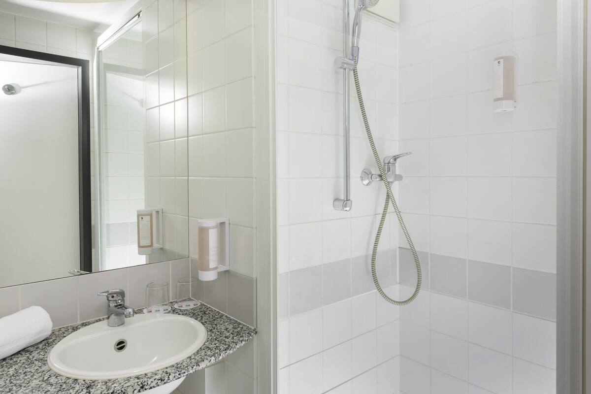 A bathroom with a sink, mirror, and shower.