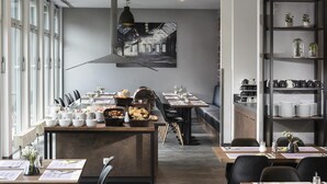 Un restaurant moderne doté d’une grande table à manger commune, de tables individuelles et d’un espace bar.
