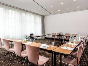 Ein Konferenzraum mit Tischen, Stühlen und Getränkeautomaten.