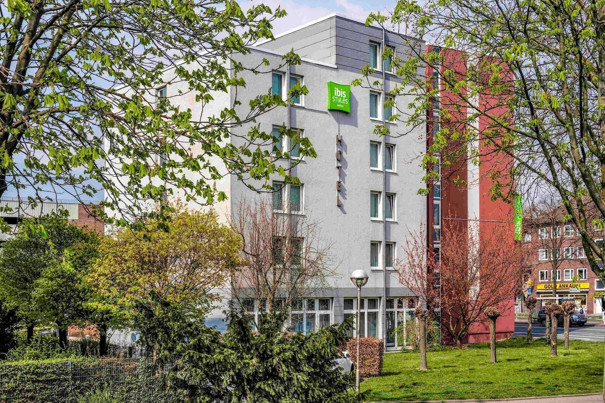 A hotel with a modern design, a sign indicating it's part of the ibis Styles hotel chain, and a visible entrance.