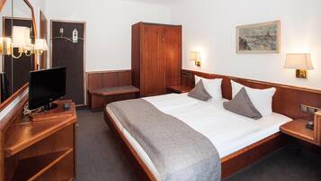 A hotel room with a large bed, a television, a wardrobe, and a painting on the wall.