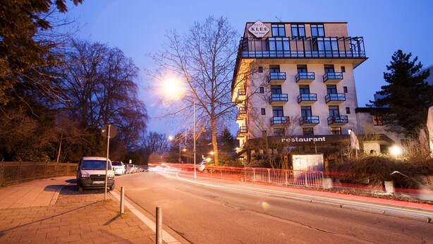 Een hotel met een restaurant op de begane grond, meerdere balkons en een modern architectonisch ontwerp.
