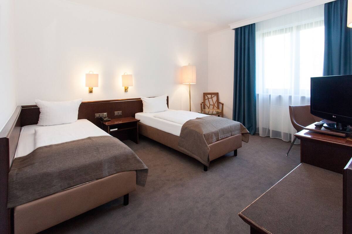 Een hotelkamer met twee bedden, een bureau, een televisie en een stoel.