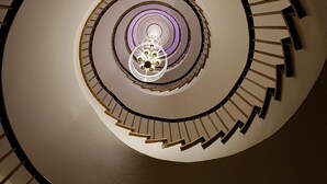 Un escalier en colimaçon doté d’un luminaire central et d’une rampe circulaire.