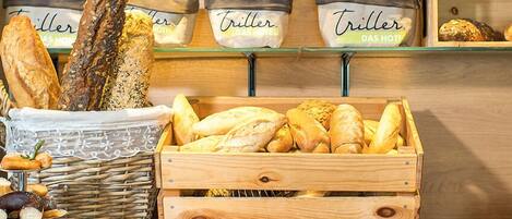 A bakery display with various types of bread, including baguettes and loaves, in wicker baskets and wooden crates.