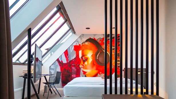 A modern bedroom with a skylight, a bed, a desk, and a chair. - Hotel Am Triller (Saarbrücken)
