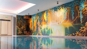 A modern interior with a large reflective pool, a vibrant mural, and a wooden slat wall. - Hotel Am Triller (Saarbrücken)