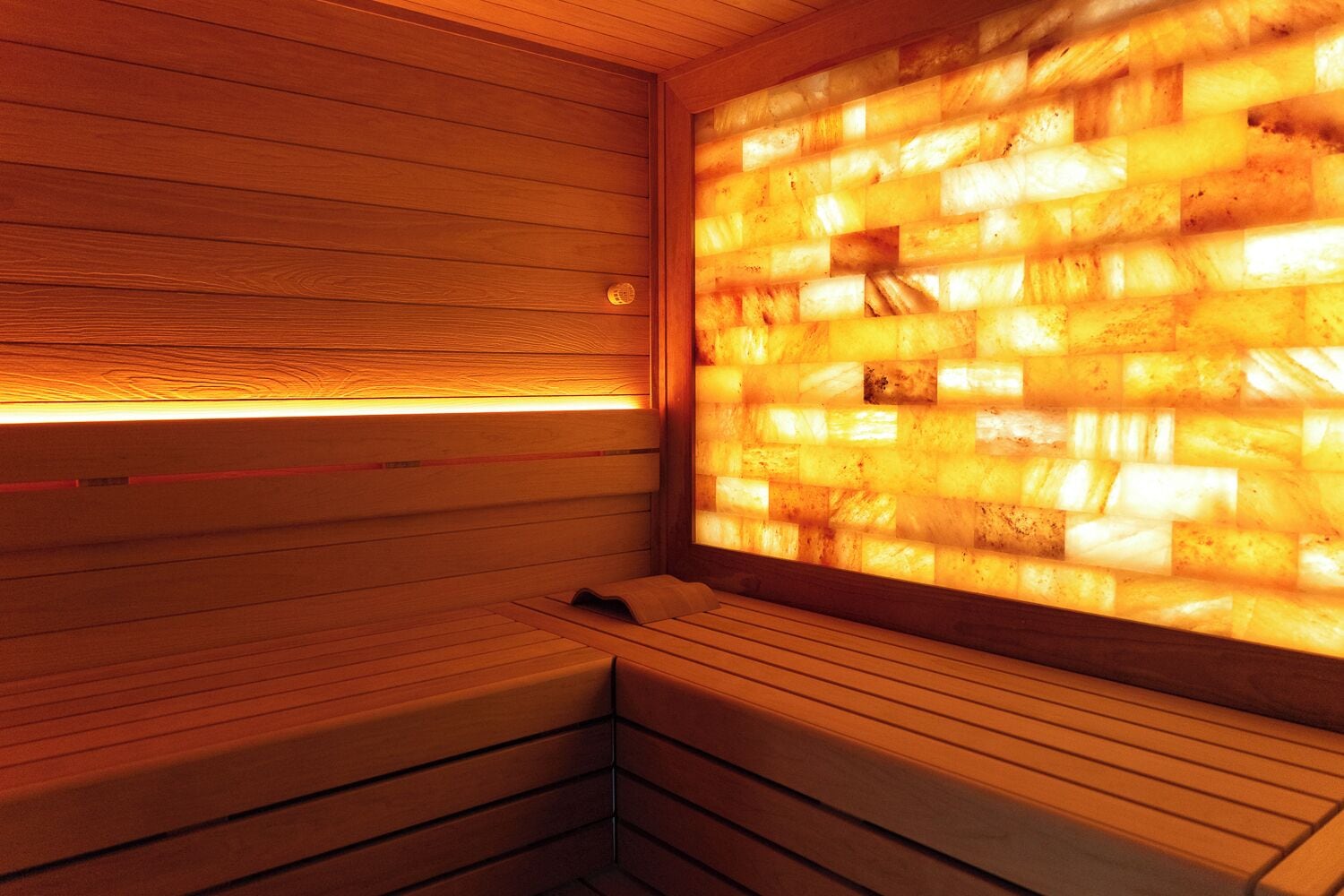 Een sauna met houten banken en een wand met een mozaïek van lichtgekleurde tegels.