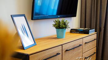 A wooden cabinet with a framed picture, a small potted plant, and a stack of books.