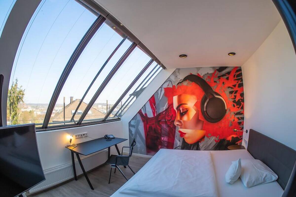 A modern bedroom with a skylight, a desk, and a bed.